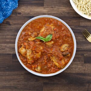 A bowl of chicken cacciatore served with pasta on the side, garnished and ready to enjoy.