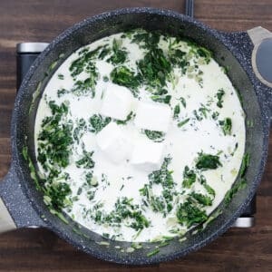 A pan with sautéed spinach combined with cream cheese and heavy cream.