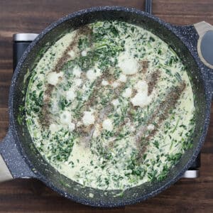 A pan of creamed spinach seasoned with black pepper, salt, and ground nutmeg.