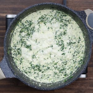 A pan of creamed spinach simmering to thicken.