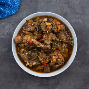 Jamaican Brown Stew Chicken served in a white bowl, ready to enjoy.