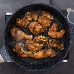 A pan with marinated chicken pieces searing to golden perfection.