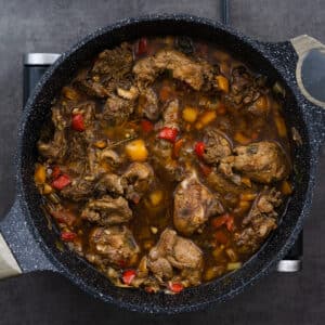 A pan with perfectly cooked Jamaican Brown Stew Chicken, rich and saucy.