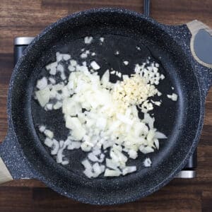 A pan with onions and garlic in oil, ready for sauteing.
