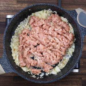 A pan with ground meat added to the onion and garlic mixture.