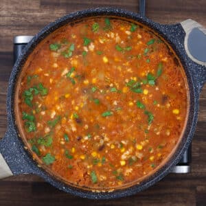 A pan with taco soup garnished with fresh cilantro leaves on top.