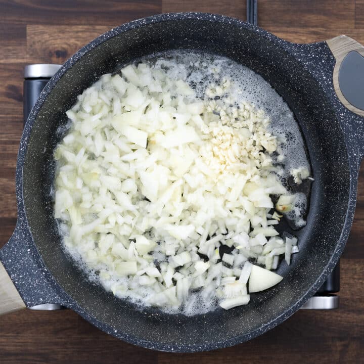 A pan with sautéed onions and garlic in melted butter.