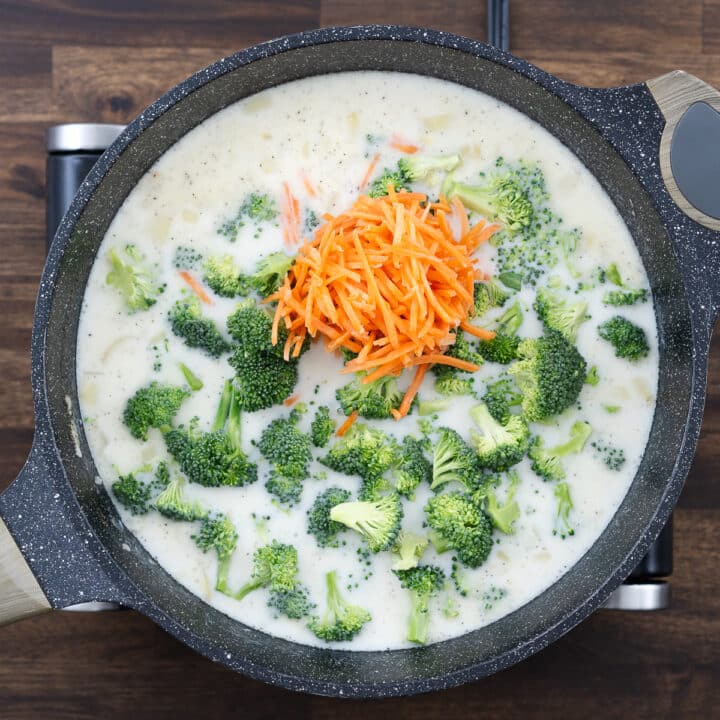 A pan with broccoli and carrots simmering in a milk and broth mixture.