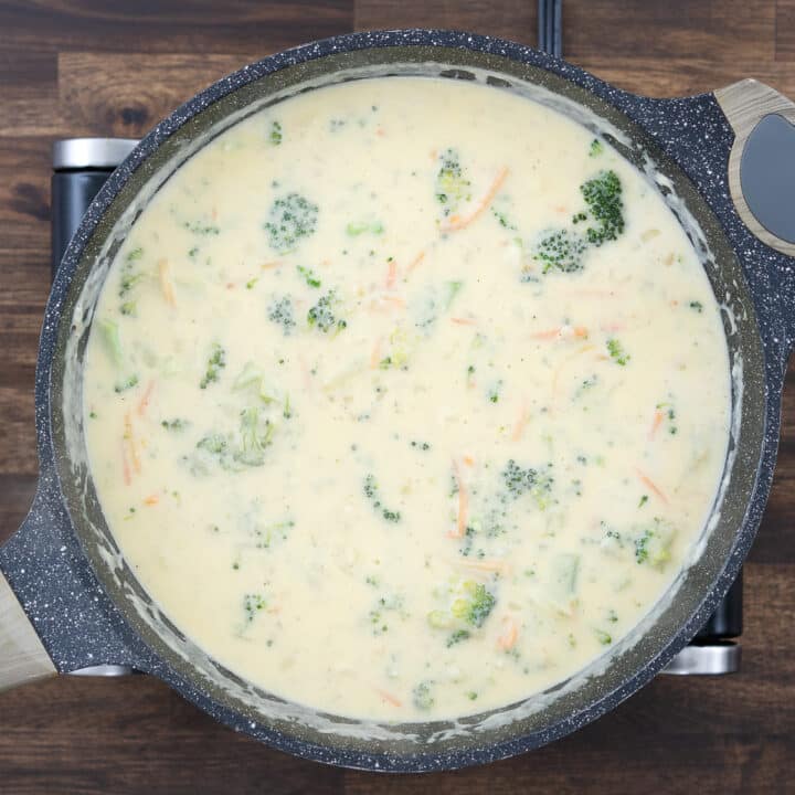 A pan filled with creamy broccoli cheddar soup, ready to be served.