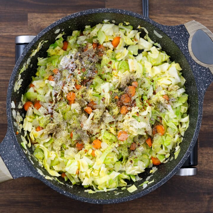 A pan with veggies and cabbage seasoned with spices. A pan with veggies and cabbage seasoned with spices.