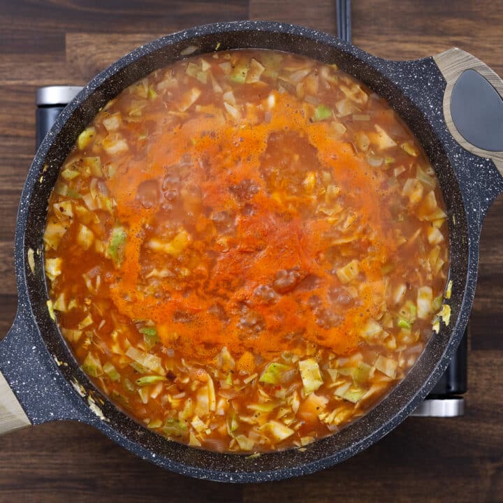 A pan with veggies and cabbage simmering in a tangy, savory broth.