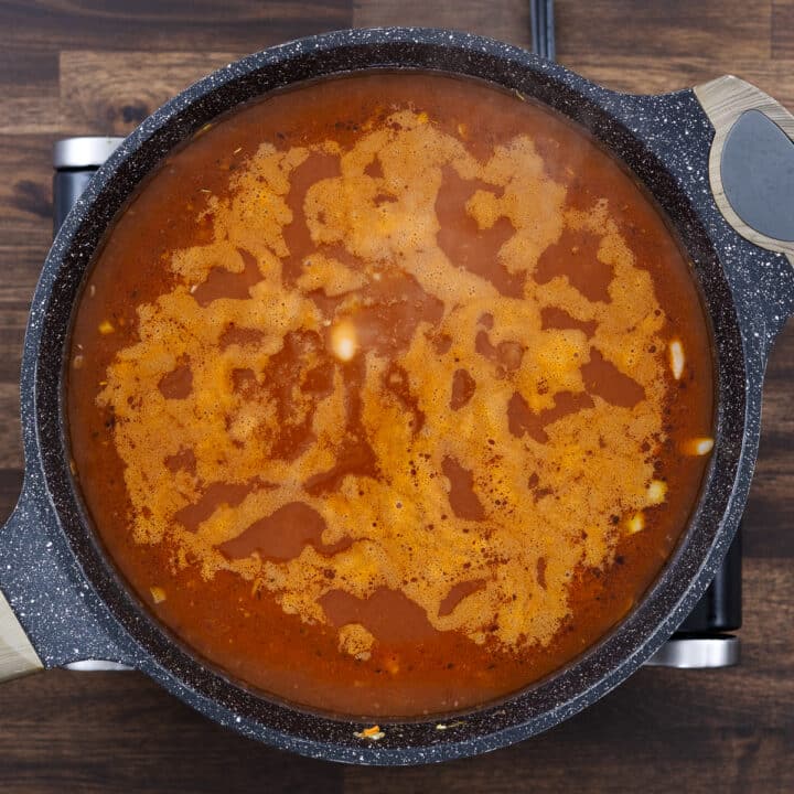 A pan with vegetables and beans simmering in a flavorful broth.