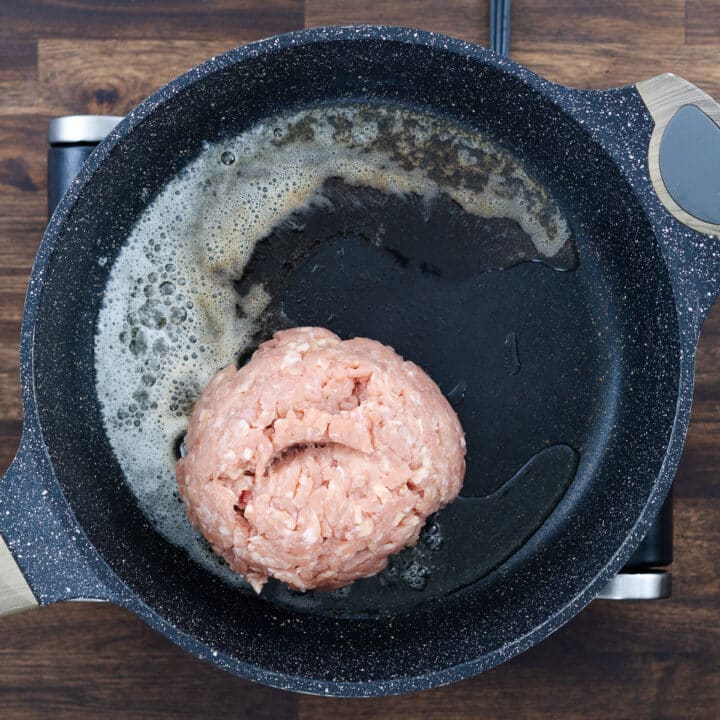 Pan with ground meat sizzling in melted butter and olive oil.