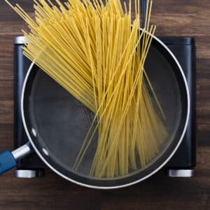 A pot with water and spaghetti pasta starting to soften in boiling water.
