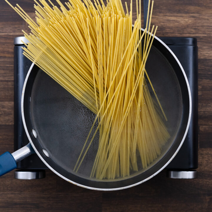 A pot with water and spaghetti pasta starting to soften in boiling water.