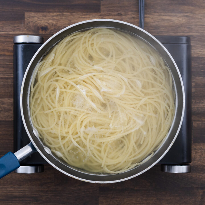 A pan with spaghetti pasta in hot boiling water, cooking to al dente.
