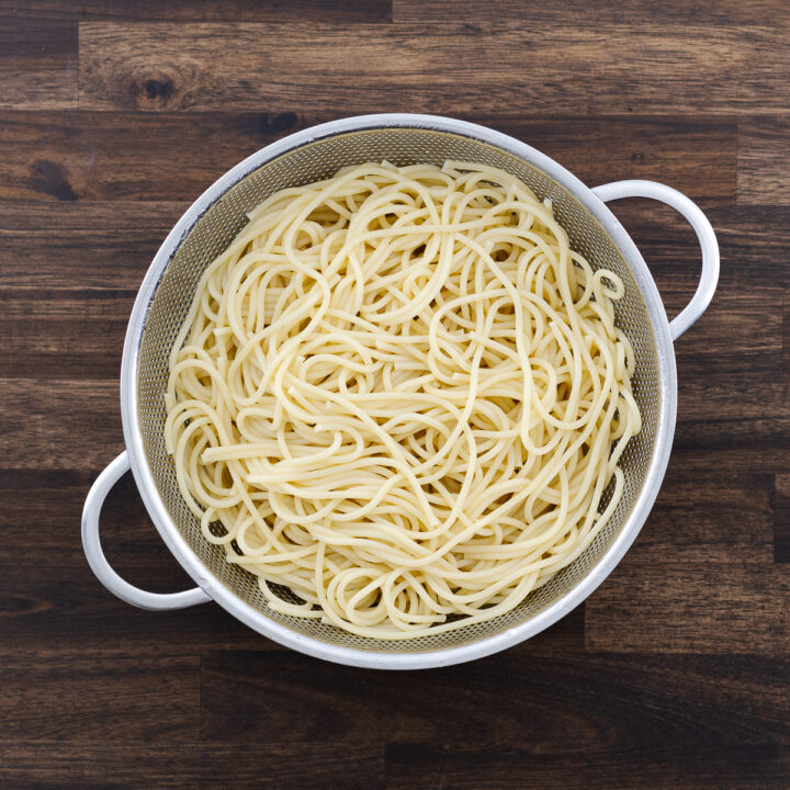 A colander with cooked pasta, ready to be tossed in garlic-infused oil.