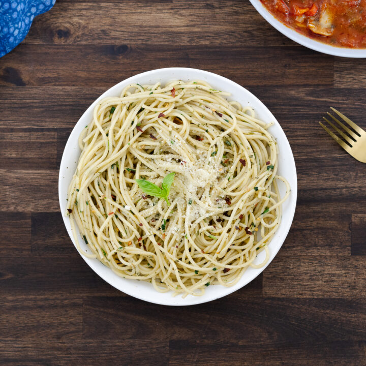 A bowl of Spaghetti Aglio e Olio served, topped with Parmesan cheese.