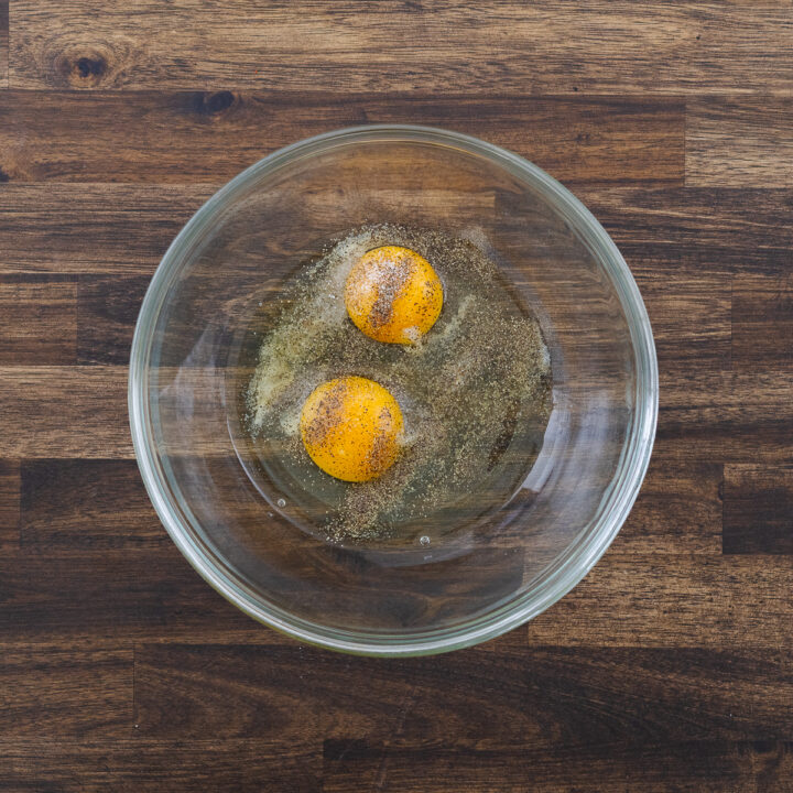 A bowl containing beaten eggs mixed with seasonings.