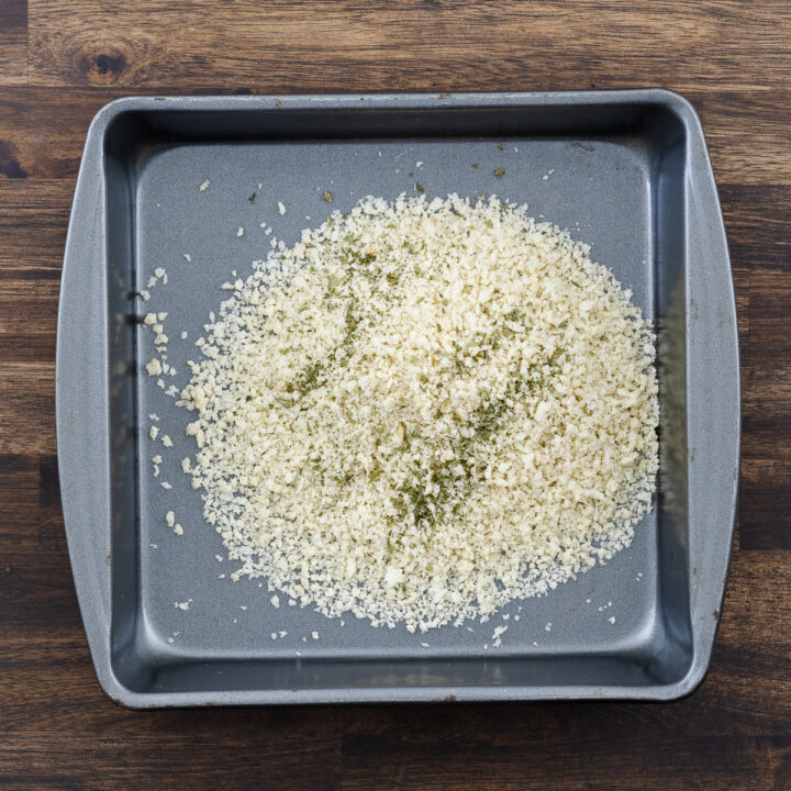 A tray with panko breadcrumbs combined with dried parsley.