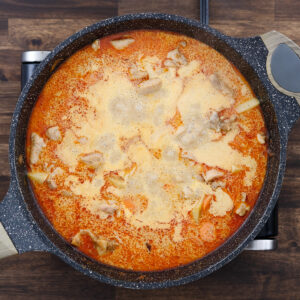 A pan with simmering curry with chicken and veggies.
