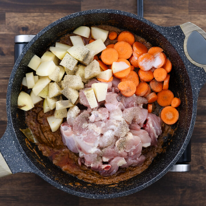 A pan with chicken, potatoes, and carrots coated in curry paste.