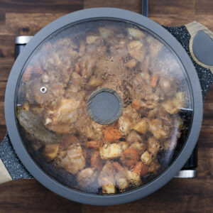 A pan covered with the lid to cook the chicken and veggies.
