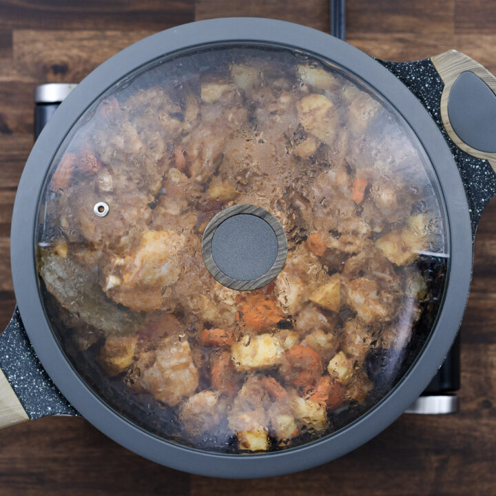 A pan covered with the lid to cook the chicken and veggies.