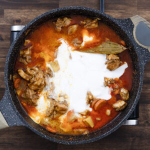 A pan with Chicken and veggies in a coconut milk and broth mixture.