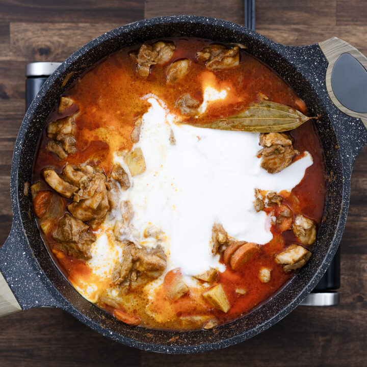 A pan with Chicken and veggies in a coconut milk and broth mixture.