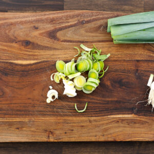 Chopped white and light green parts of leeks on a wooden cutting board, ready for cooking.
