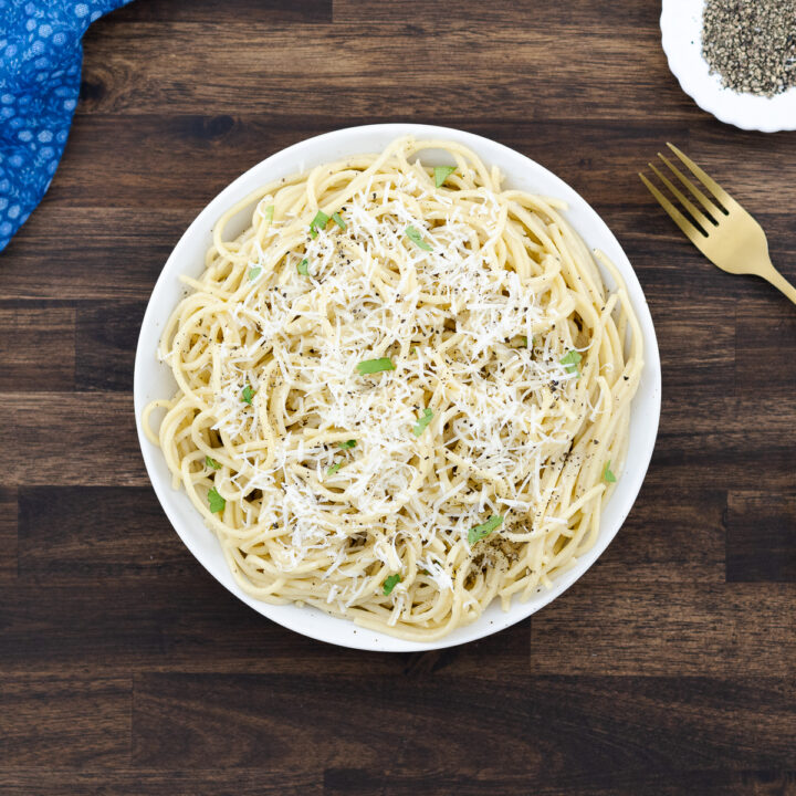 Cacio e Pepe served in a white bowl, topped with extra grated Pecorino Romano cheese.