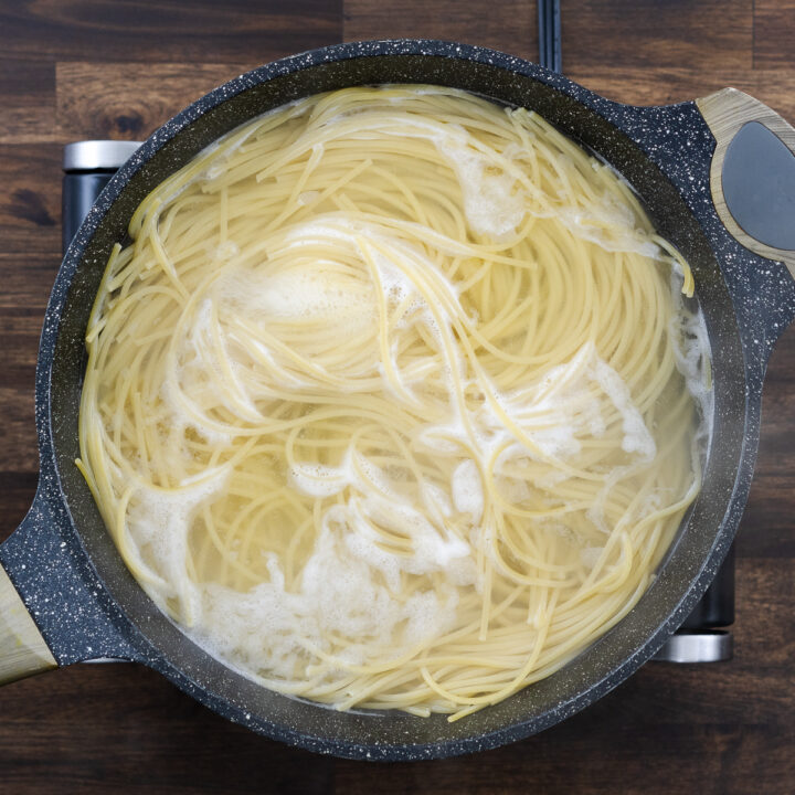 A pot with spaghetti pasta cooking in water.