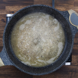A pan with pasta cooking water in the butter and black pepper mixture.