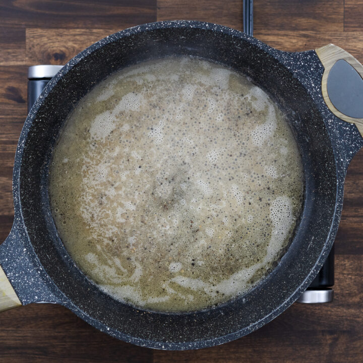 A pan with pasta cooking water in the butter and black pepper mixture.