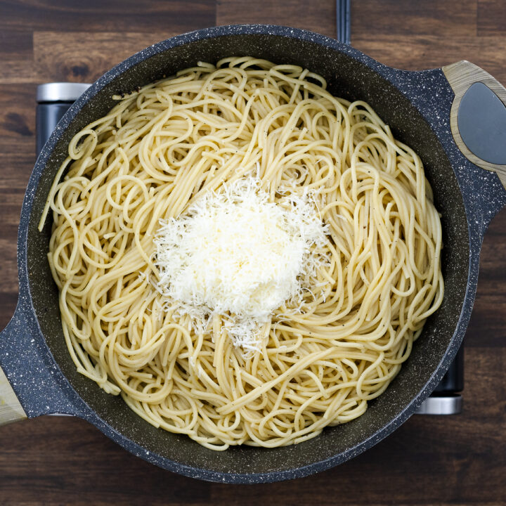 A pan with spaghetti pasta and freshly grated Pecorino Romano cheese.