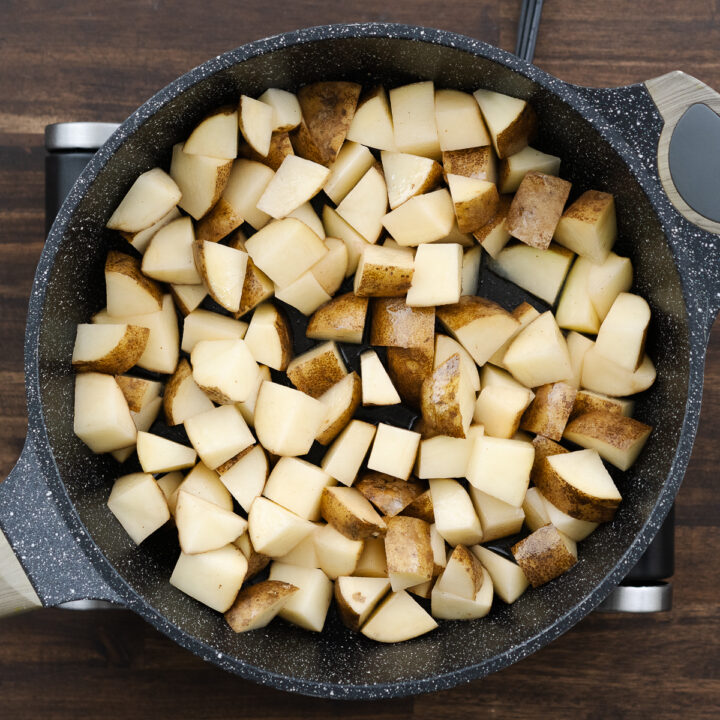 Pan with diced potatoes in oil ready for frying.