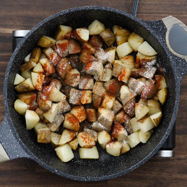 Pan with crisped potatoes seasoned with pantry seasonings like paprika, black pepper, onion powder, garlic powder, and salt.