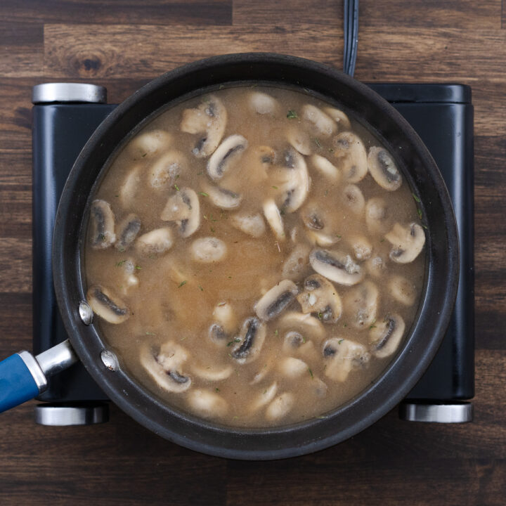 Mushroom and broth mixture in a pan, ready to cook.
