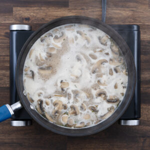Mushroom gravy simmering in broth on the stove.