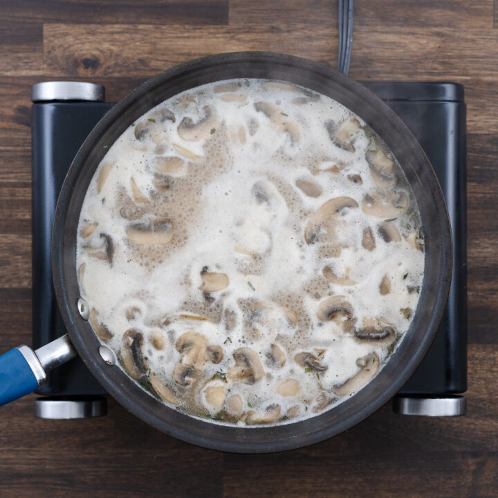 Mushroom gravy simmering in broth on the stove.