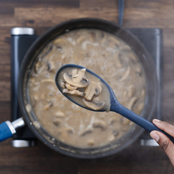 Thick mushroom gravy shown in a blue spoon to highlight its smooth consistency.