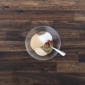 A bowl of spice powder, ready to be mixed with a spoon for seasoning the chicken breast.