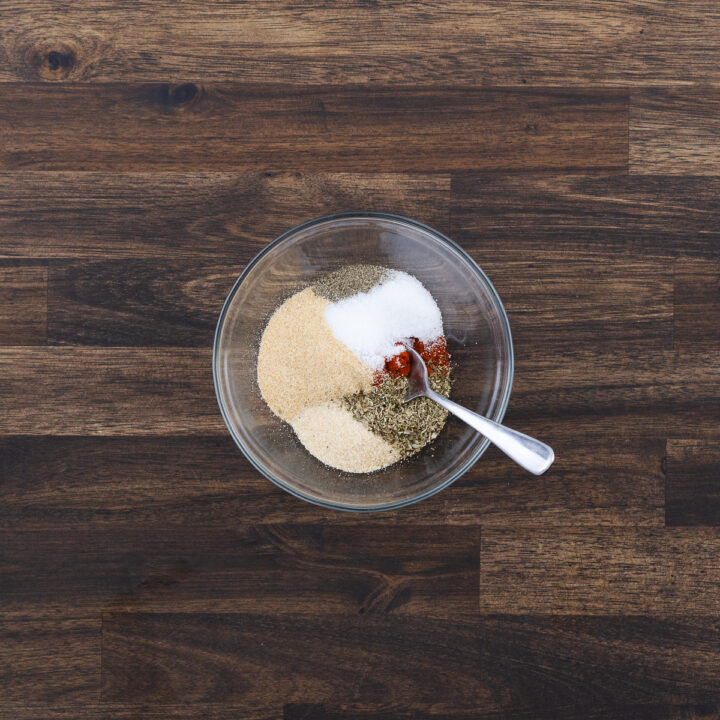 A bowl of spice powder, ready to be mixed with a spoon for seasoning the chicken breast.