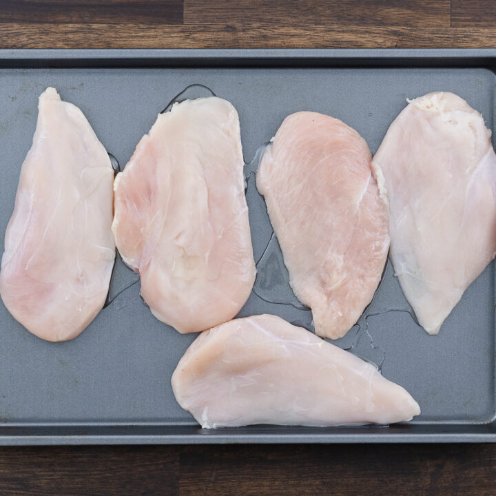 A tray with thinly sliced chicken breast lightly coated with oil.